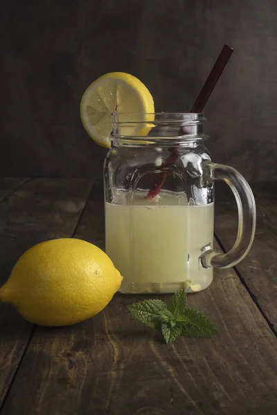 Vaso di vetro alla limonata con spicchi di limone e paglia — Foto Stock