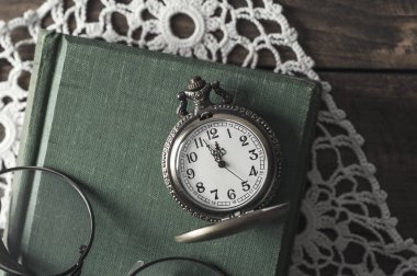 Bir antika köstekli saati, gözlük ve kitaplar