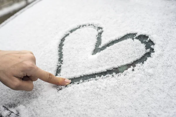 Coração desenhado em um pára-brisas de carro coberto de neve fresca . — Fotografia de Stock