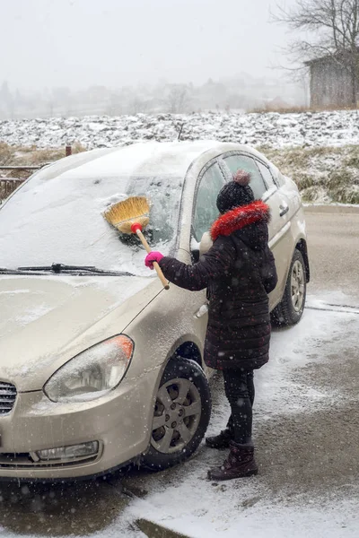 車から雪をブラシにかわいらしい子供. — ストック写真