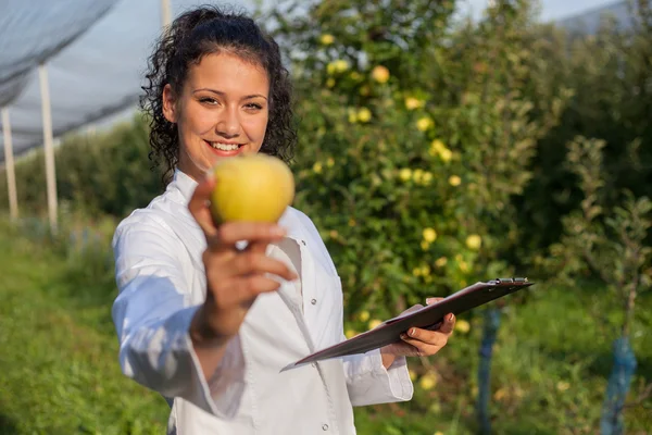 Szczęśliwa młoda kobieta agronom z zielonego jabłka w ręku — Zdjęcie stockowe