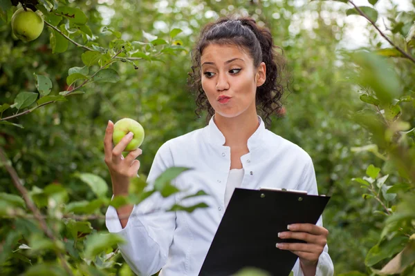 Улыбающийся агроном с тетрадью, стоящей в яблоневом саду — стоковое фото