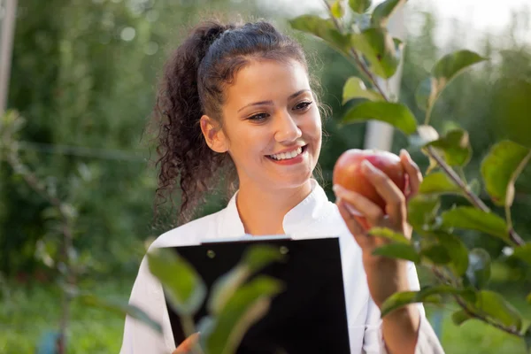 Gelukkig jonge vrouw agronoom met rode appel in haar hand — Stockfoto