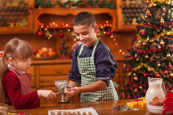 Bonito menino e menina preparando biscoitos de Natal em casa — Fotografia de Stock