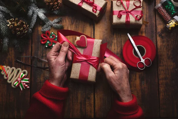 Руки пожилой женщины, делающей новогодние или рождественские подарки — стоковое фото