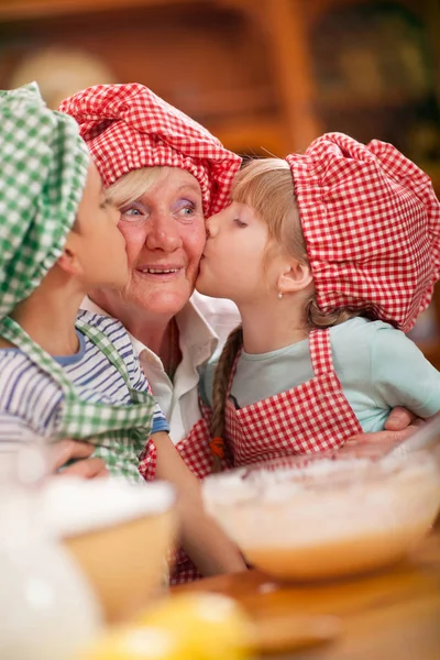 Nieto y nieta besar a su abuela en la cocina — Foto de Stock