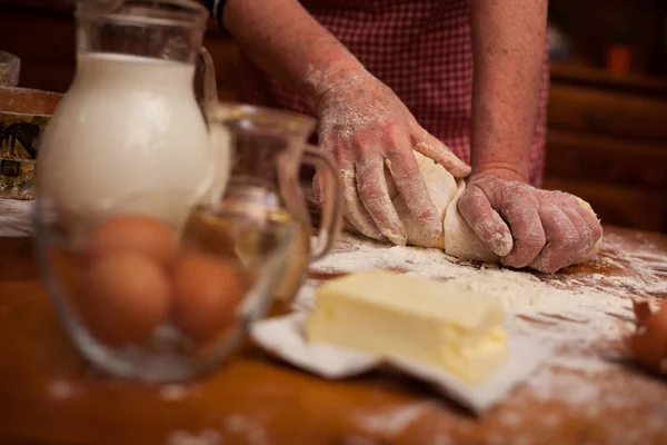 Las manos ancianas amasan la masa en la mesa en la cocina casera —  Fotos de Stock