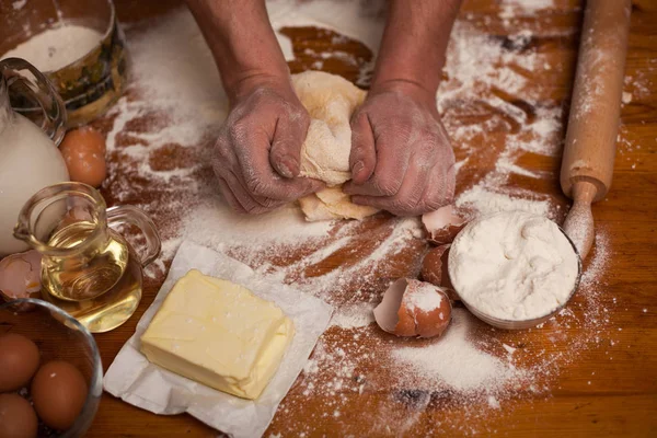 Mãos de homem sênior amassar massa na mesa na cozinha em casa — Fotografia de Stock