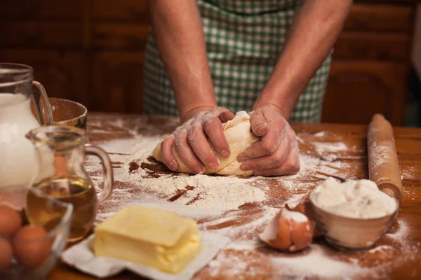 Mãos de homem sênior amassar massa na mesa na cozinha em casa — Fotografia de Stock