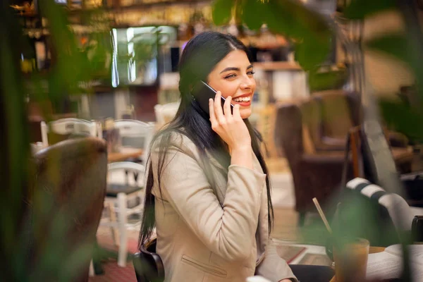 Café'de cep telefonuyla konuşurken kullanan kadın — Stok fotoğraf