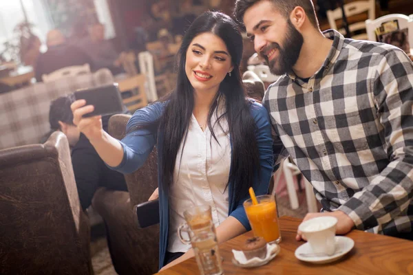 Et par som tar selfie med kameratelefon på kafe stockfoto