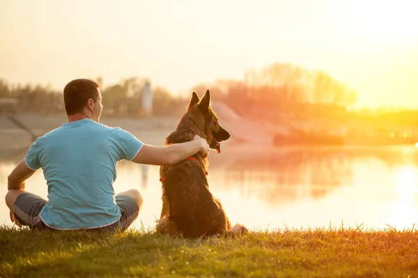 Homem e cão relaxados desfrutando do pôr do sol de verão ou nascer do sol — Fotografia de Stock