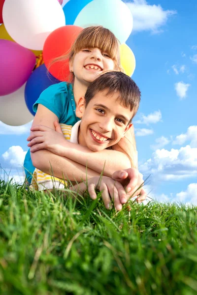 Счастливые улыбающиеся дети, лежащие на зеленой траве с цветными — стоковое фото