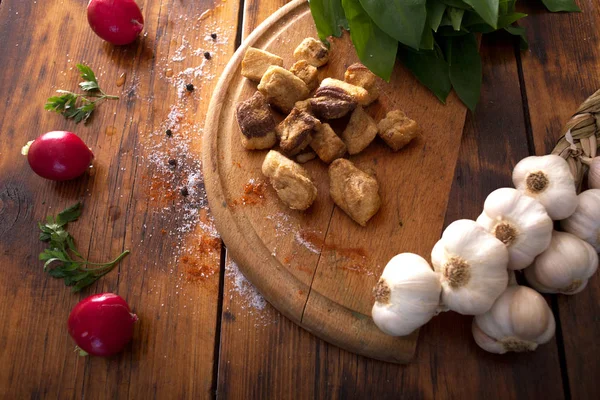 Grieben auf Holzgrund mit Knoblauch und Radieschen — Stockfoto