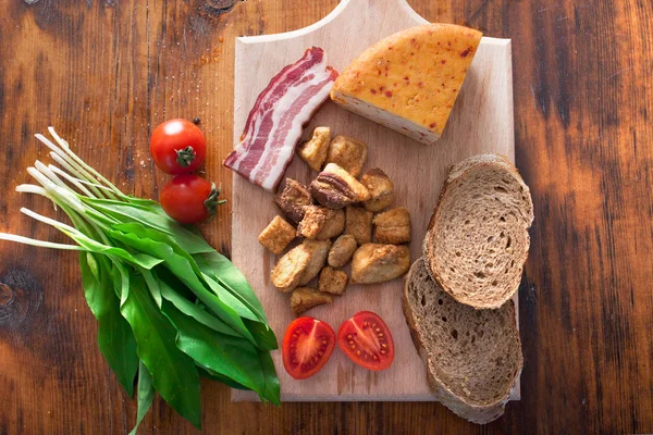 Schweinegrieben Käse und Speck auf Holzgrund — Stockfoto