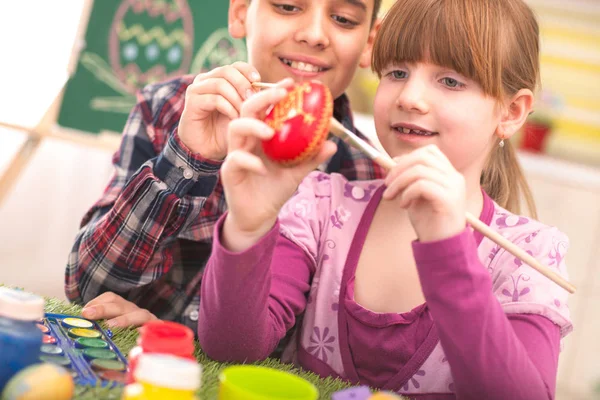 Fröhliche Jungen und Mädchen spielen mit Ostereiern — Stockfoto