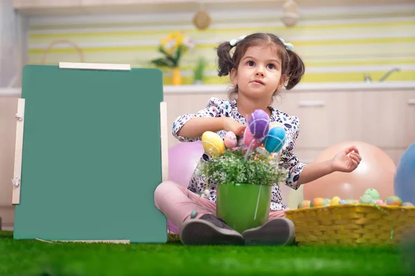 Schattig klein meisje met mand vol kleurrijke paaseieren — Stockfoto