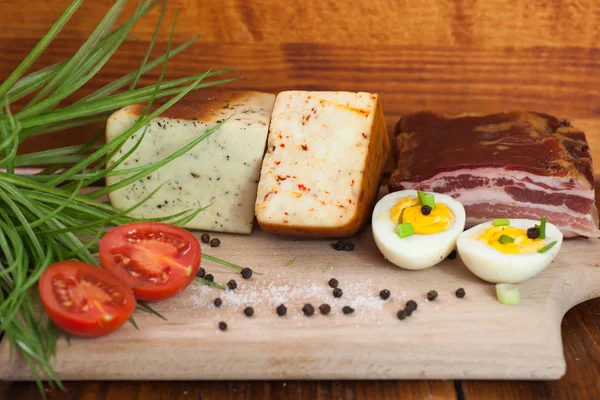 Tocino, queso y tomate en un plato de madera —  Fotos de Stock