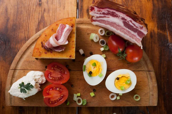 Speck, Käse und Tomaten auf Holzteller — Stockfoto