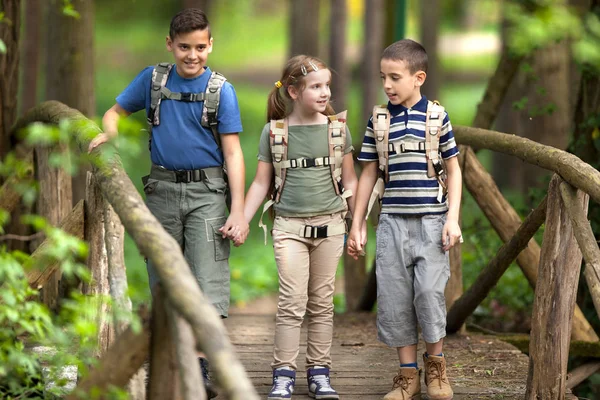 Kids scouts traveler with backpack hiking bridge in forest — Stock Photo, Image