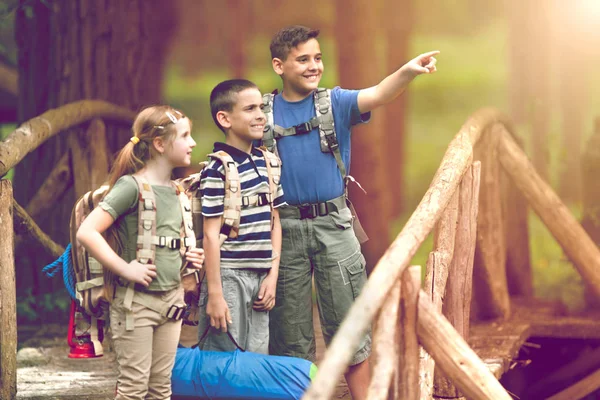 Kids scouts traveler with backpack hiking on bridge — Stock Photo, Image
