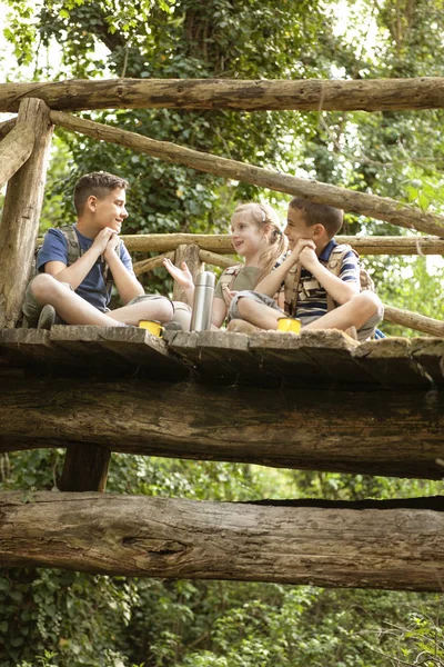 Young scouts sitting on old wooden bridge in the woods — Stock Photo, Image