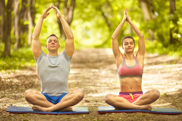 Jeune couple relaxant dans la pose de yoga dans la nature verte — Photo