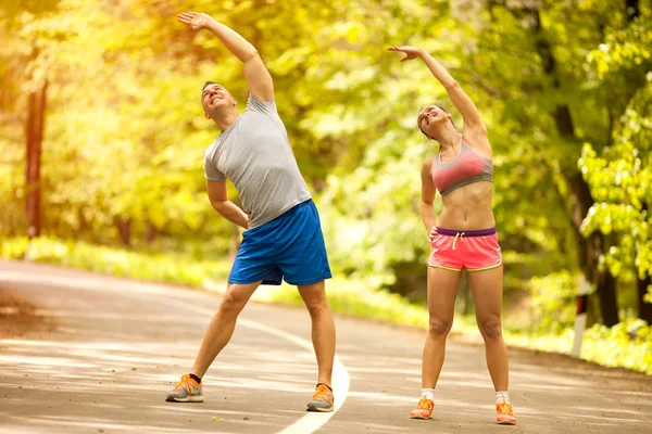 Giovane sorridente felice coppia fitness nella foresta — Foto Stock