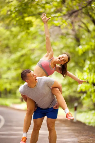 Mladý, usměvavý fitness šťastný pár v lese — Stock fotografie