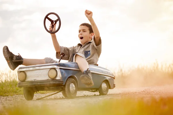 Garoto menino condução grande brinquedo vintage carro com um ursinho de pelúcia — Fotografia de Stock