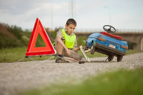 Helpen op de weg, een jongen met zijn speelgoedauto — Stockfoto