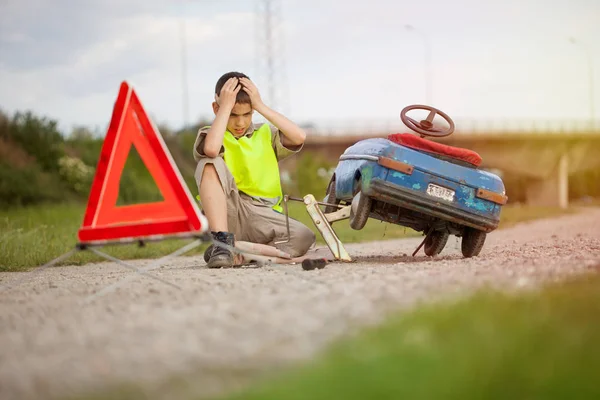 Aider sur la route, un jeune garçon avec sa voiture jouet — Photo