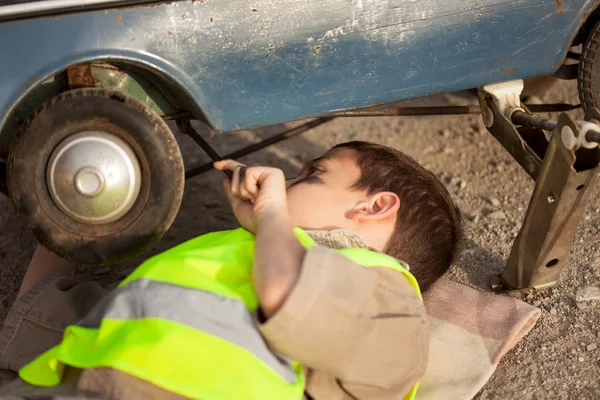 少年は、古いおもちゃの車のタイヤを変更します。 — ストック写真