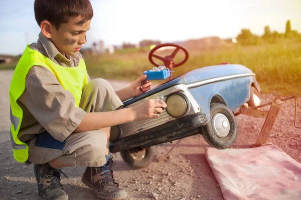 Мальчик меняет лампочки на своей ретро игрушечной машине — стоковое фото