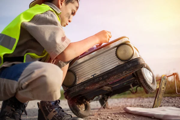 Junge wechselt Glühbirnen an seinem Retro-Spielzeugauto — Stockfoto