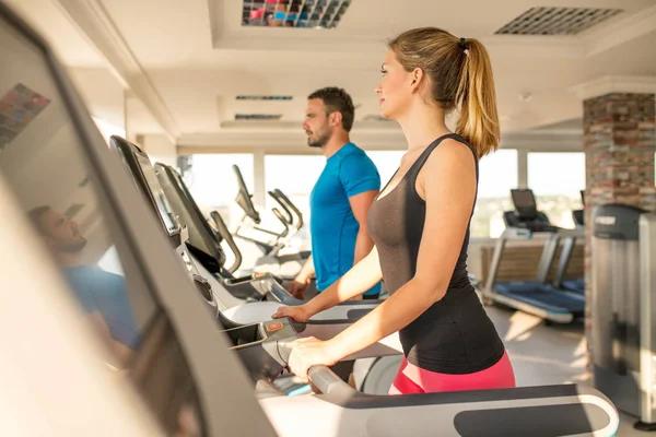 Young man and woman biking in the gym, exercising legs doing car — Stock Photo, Image