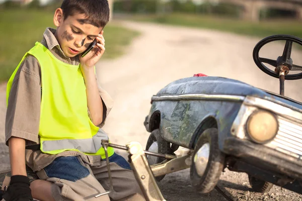 Divertente ragazzo con auto giocattolo chiamando dal telefono cellulare assistenza stradale — Foto Stock