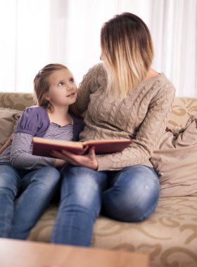 mutlu aile, anne ve kızı evde bir kitap okumak