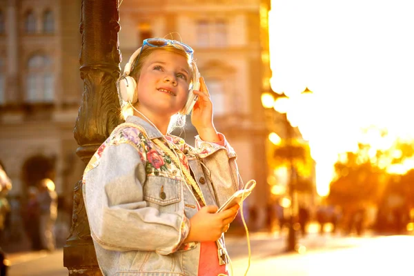 Słuchania muzyki bardzo młoda dziewczyna z jej słuchawki w st — Zdjęcie stockowe