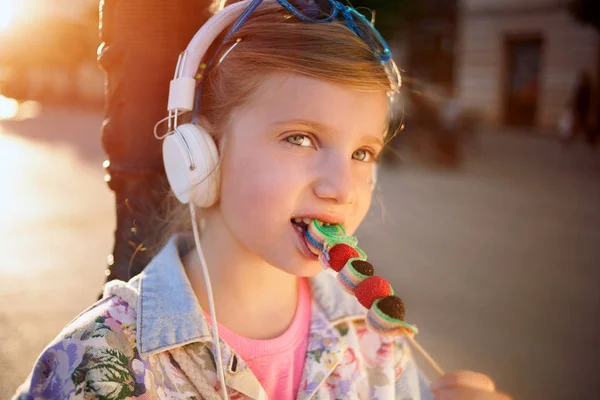Niña escuchando música y comiendo piruleta de frutas, beauti — Foto de Stock