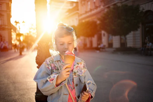 Menina ouvindo música na rua e comer sorvete — Fotografia de Stock