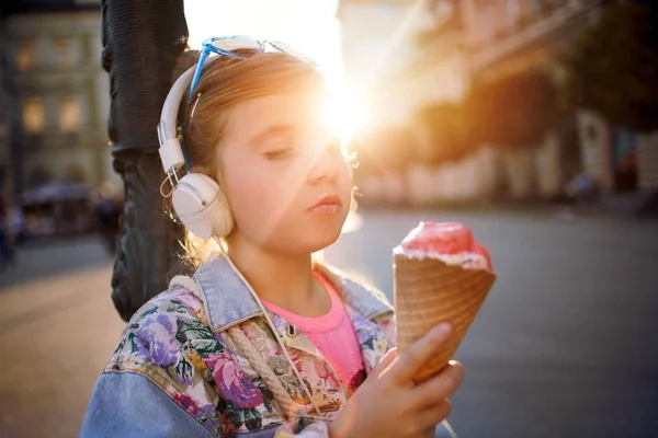 Menina ouvindo música na rua e comer sorvete — Fotografia de Stock