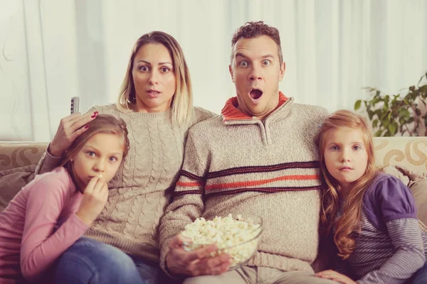 Beautiful young parents and their children are watching TV, eati — Stock Photo, Image