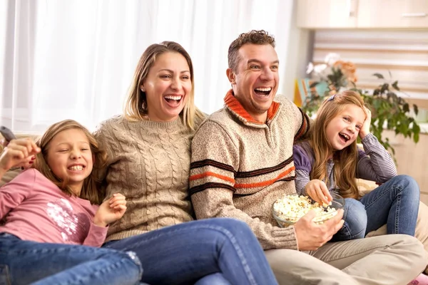 Beautiful young parents and their children are watching TV, eati — Stock Photo, Image