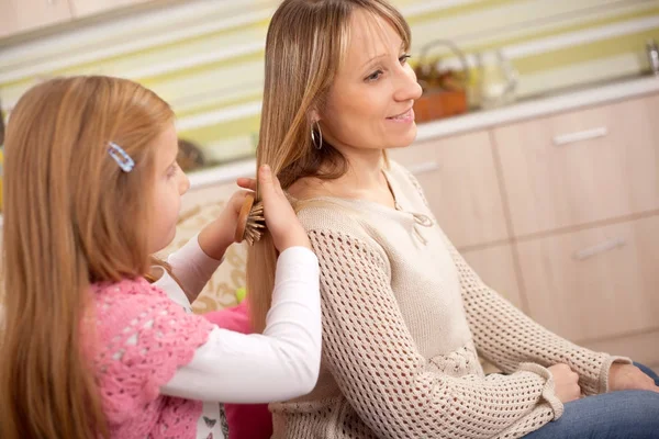 Figlia pettinando i capelli di sua madre in camera — Foto Stock