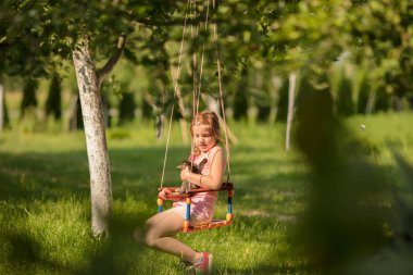 Küçük çocuk sarışın kız salıncak ile eğleniyor