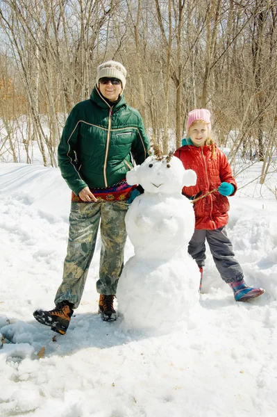 Anne ve kızı bir kardan adam yanında Telifsiz Stok Fotoğraflar