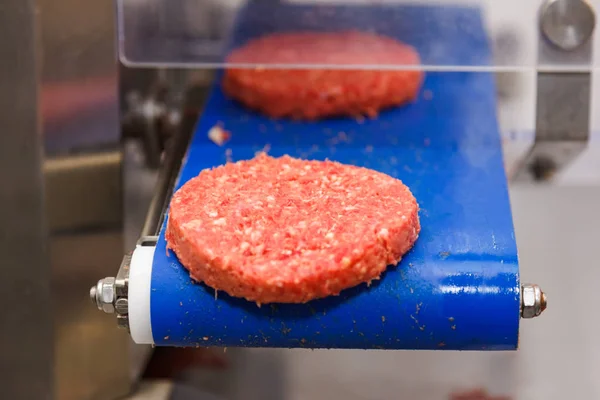 Carne de hambúrguer na correia transportadora — Fotografia de Stock