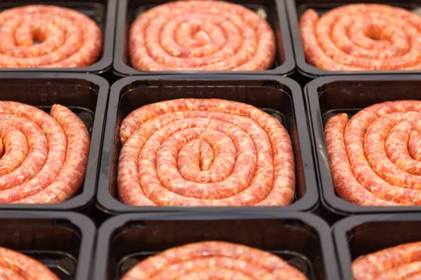 Rolled raw meat sausages in packing box — Stock Photo, Image