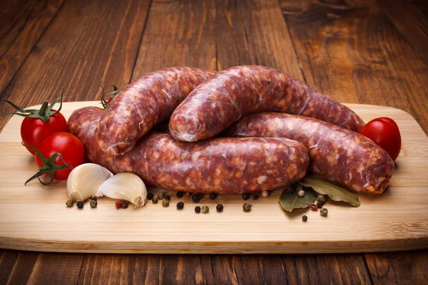 Saucisses épaisses de porc cru sur planche à découper — Photo